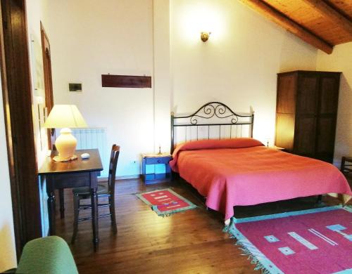 a bedroom with a bed and a desk and a table with a lamp at Case Zuccaro in Trecastagni