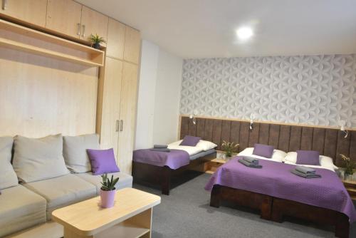 Habitación de hotel con 2 camas y sábanas moradas. en Penzion Klimeš en Hustopeče