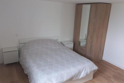 1 dormitorio con cama blanca y armario de madera en Maison à proximité de la ville avec jardin clôturé, en Casseneuil