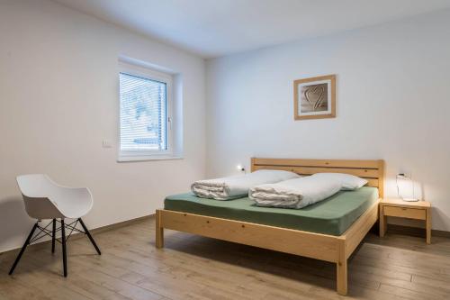 ein Schlafzimmer mit einem Bett, einem Stuhl und einem Fenster in der Unterkunft Talhaus - Robert in Ponte Nova