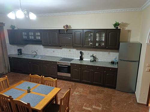 cocina con armarios negros, mesa y nevera en Savvas&Katia's luxury house en Mantoúkion