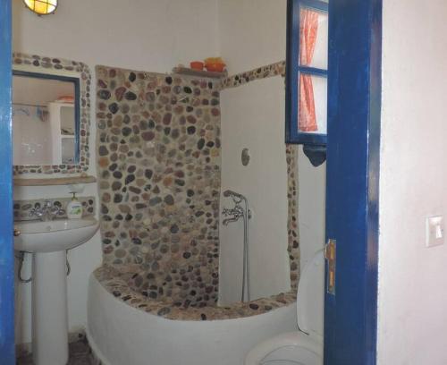a bathroom with a stone shower and a sink at Arancio independent room in Ecovilla on the beach in Apolakkiá