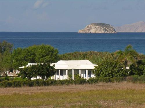 ein weißes Haus vor dem Meer in der Unterkunft Arancio independent room in Ecovilla on the beach in Apolakkiá