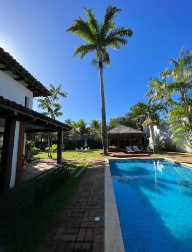 a swimming pool in front of a house with a palm tree at Hotel Casa Paradiso Guarujá in Guarujá