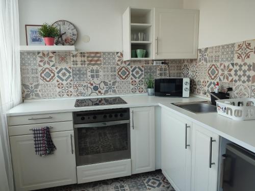 a kitchen with white cabinets and a stove top oven at Palota Apartman in Gödöllő