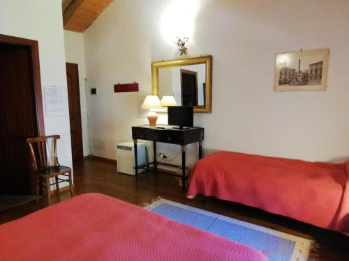 a room with two beds and a desk with a mirror at Case Zuccaro in Trecastagni