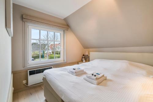 Un dormitorio con una cama blanca con toallas. en Luxe familievilla voor 9pers met zee en tuinzicht, en Koksijde