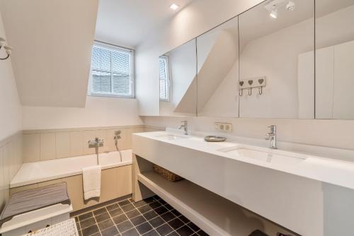 uma casa de banho com 2 lavatórios e um espelho grande em Luxe familievilla voor 9pers met zee en tuinzicht em Koksijde