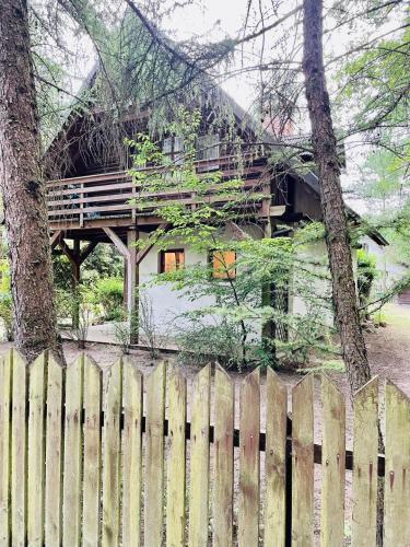 a wooden house behind a fence with a tree at Domek letniskowy na Mazurach in Jerutki