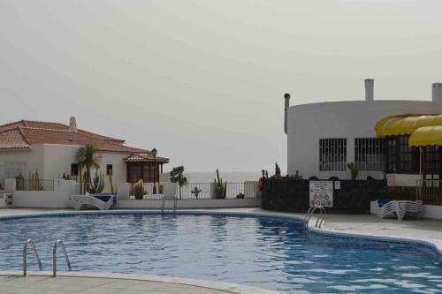 a swimming pool with umbrellas next to a building at Villa Tranquila, Playa del Duque in Adeje