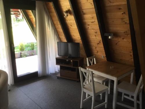 a dining room with a table and a television in a cabin at Gemütliches Ferienhaus mit sonniger Terrasse Frankenwald nähe Badesee Smart-TV in Lichtenberg