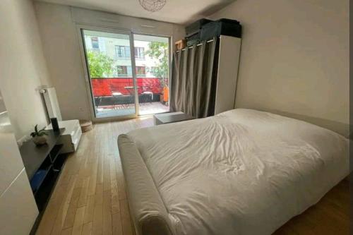 een slaapkamer met een wit bed en een groot raam bij Studio 30m2 near Paris in Boulogne-Billancourt