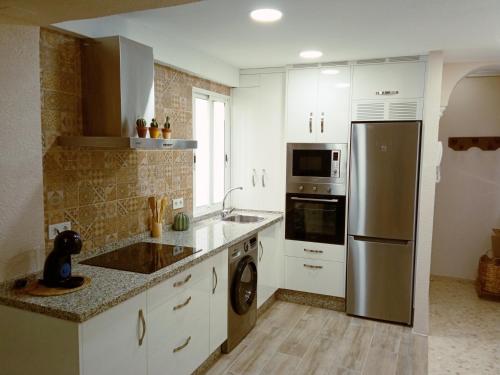 a kitchen with white cabinets and a stainless steel refrigerator at Apartamento La Viñuela in Córdoba