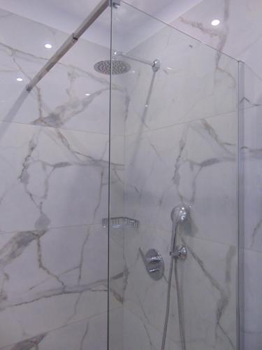 a shower stall with a glass door with a shower at Sweetmar guest Rooms-ground floor in Kos Town