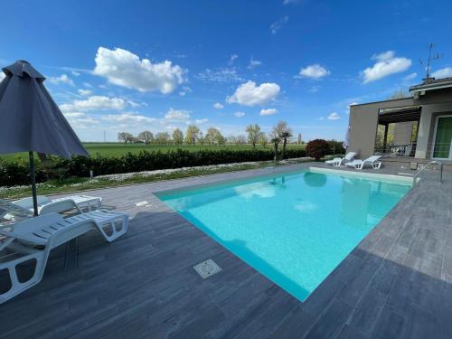 a swimming pool with chairs and an umbrella at Ca Giuliocesare in Castiglione di Ravenna