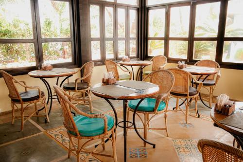 a restaurant with tables and chairs in a room with windows at Anauí Pousada in Porto De Galinhas