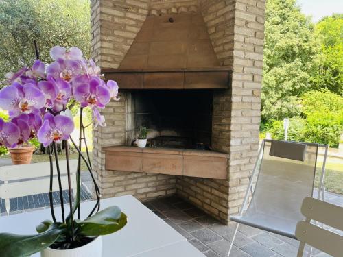 un horno de piedra para pizzas en un patio con flores púrpuras en Il borgo fra i laghi en Monzambano