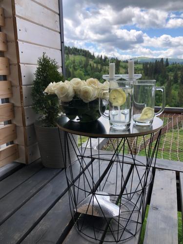 a table with roses and glasses on a balcony at Карпатське Hygge in Slavske