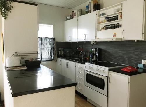 una cucina con armadi bianchi e piano di lavoro nero di Nice holiday home in Tallbacken outside Ljungby a Bolmstad