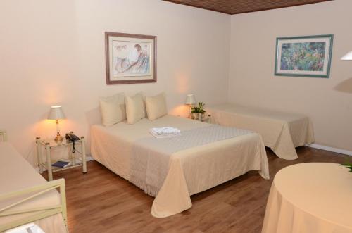 a bedroom with two beds and two tables with lamps at Skalla Hotel Nova Odessa in Nova Odessa