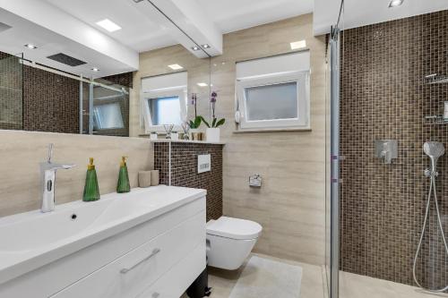 a bathroom with a sink and a toilet and a shower at Apartman GLOW in Makarska