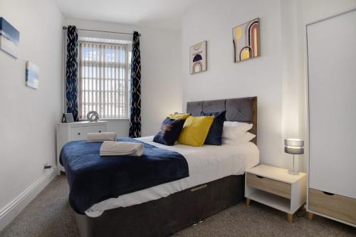 um quarto com uma cama grande com almofadas azuis e amarelas em Beautiful Cottage in Wolsingham, Perfect for families! Sleeps 6 em Bishop Auckland