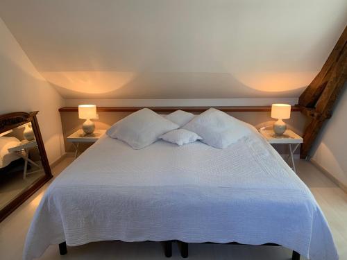 a bedroom with a large white bed with two lamps at La Villa Flore in Saint-Jouin-Bruneval