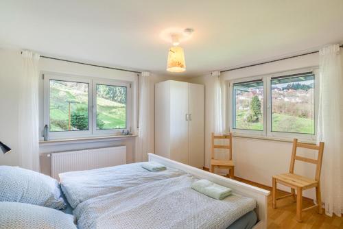 a bedroom with a bed and two windows at Ferienwohnung Dusamos in Bühlertal