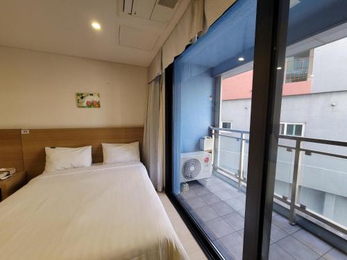 a bedroom with a bed and a large window at BK Hotel Jeju in Seogwipo