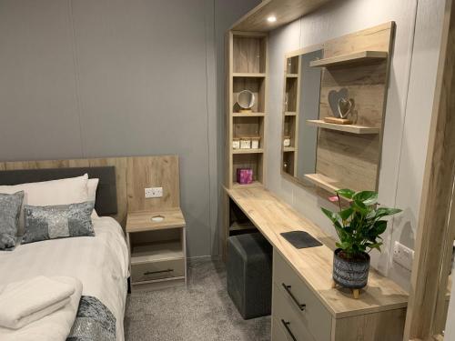 a bedroom with a bed and a desk with a plant at Bay Tree Lodge: Lakeside lodge w/hot tub & cinema surround sound in Woodhall Spa