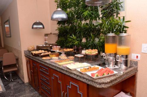 a breakfast buffet with food and drinks on a counter at Skalla Hotel Nova Odessa in Nova Odessa