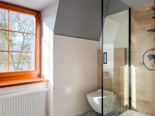 a bathroom with a toilet and a glass shower at Dwór Jeziory Wielkie 