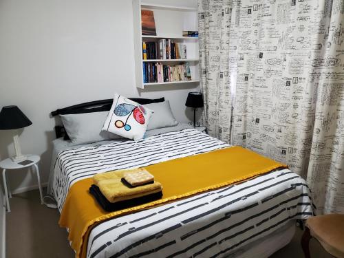 a small bedroom with a bed with a yellow and white blanket at Gateway to the Surf Coast and Geelong in Geelong