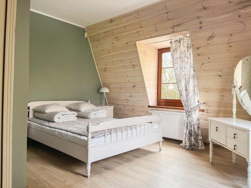a bedroom with a white bed and a wooden wall at Dwór Jeziory Wielkie in Jeziory Wielkie