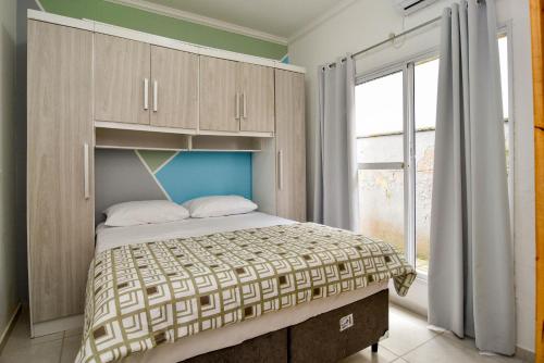 um quarto com uma cama e uma grande janela em Apto a 1 km do Beto Carrero, 600m da Praia da Armação do Itapocorói P2398 em Penha