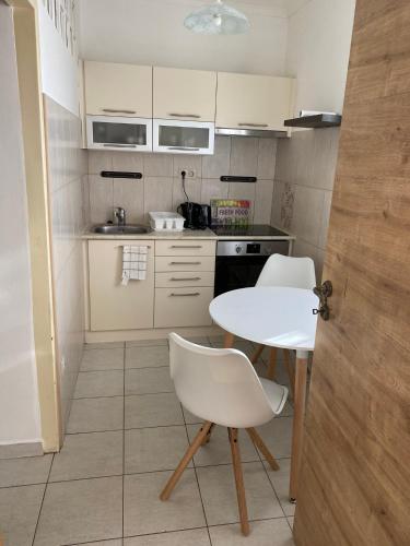 a small kitchen with a white table and chairs at Peter Apartman in Szeged