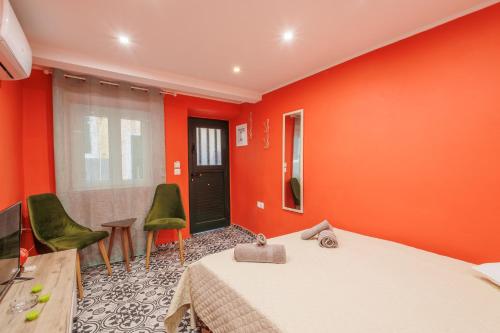 a bedroom with orange walls and green chairs at Casa Lefteritsa in Corfu