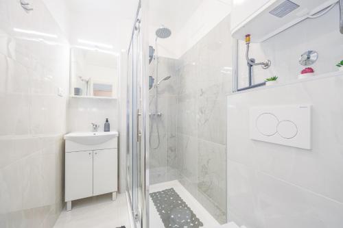 a white bathroom with a shower and a sink at Sunny apartment ILI near Amfiteatar in Pula