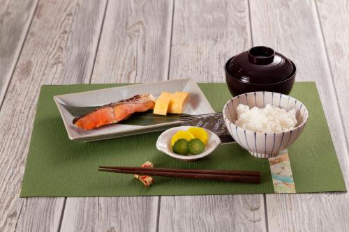 een bord sushi en een kom rijst en stokjes bij ホテルDEN in Tokyo