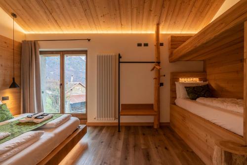 a bedroom with two beds and a window at Casera Pian Grand Wellness Lodge in Chies dʼAlpago