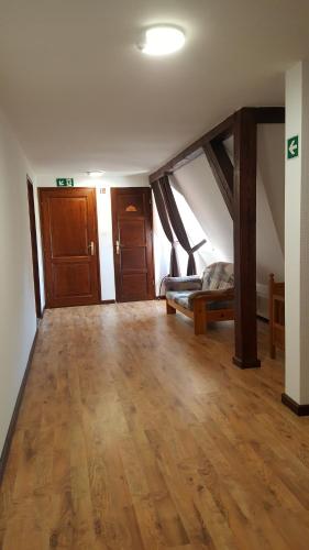a living room with a wooden floor and a bed at Visnyó Vendégház in Nagyvisnyó