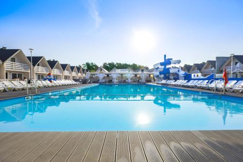 a large swimming pool at a resort with chairs at Holiday Park & Resort Niechorze in Niechorze