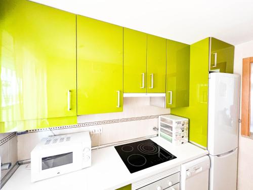 a kitchen with yellow cabinets and a white refrigerator at Renovated apartment on the first line in Oropesa del Mar