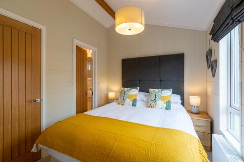 a bedroom with a large bed with a yellow blanket at Lakeside 4 Lodge in Windermere