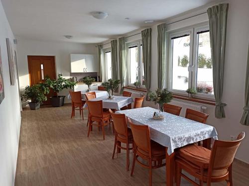 a dining room with tables and chairs and windows at Penzion U Vody in Horní Bečva