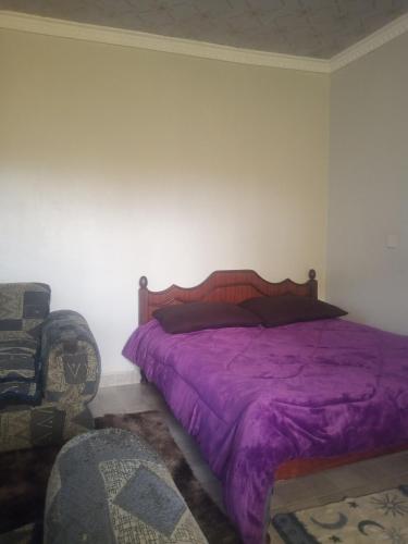 a bedroom with a purple bed and a chair at Airbnb in Nakuru