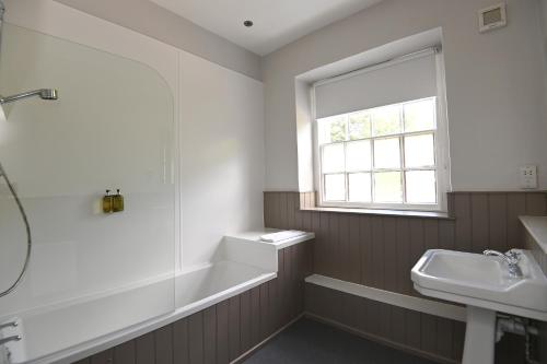 baño con bañera, lavabo y ventana en Wheatsheaf, Baslow by Marston's Inns, en Baslow