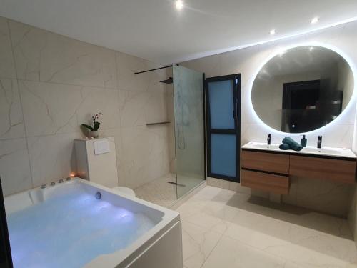 ein Badezimmer mit einer Badewanne, einem Waschbecken und einem Spiegel in der Unterkunft Mont-Vert exotique - Calme - Vue et PARKING in Saint-Pierre