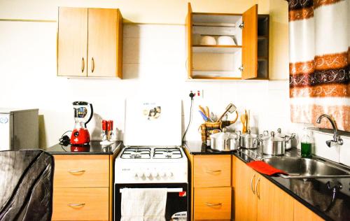La cuisine est équipée de placards en bois et d'une cuisinière blanche. dans l'établissement Affordable furnished apartments at the city centre, à Nairobi