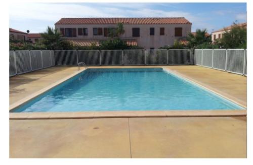 een groot zwembad met blauw water in een tuin bij Villa 6p climatisée proche mer piscine equipements nautique in Le Barcarès
